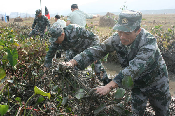 人武部干部职工为驻地村民清淤泥建水渠。